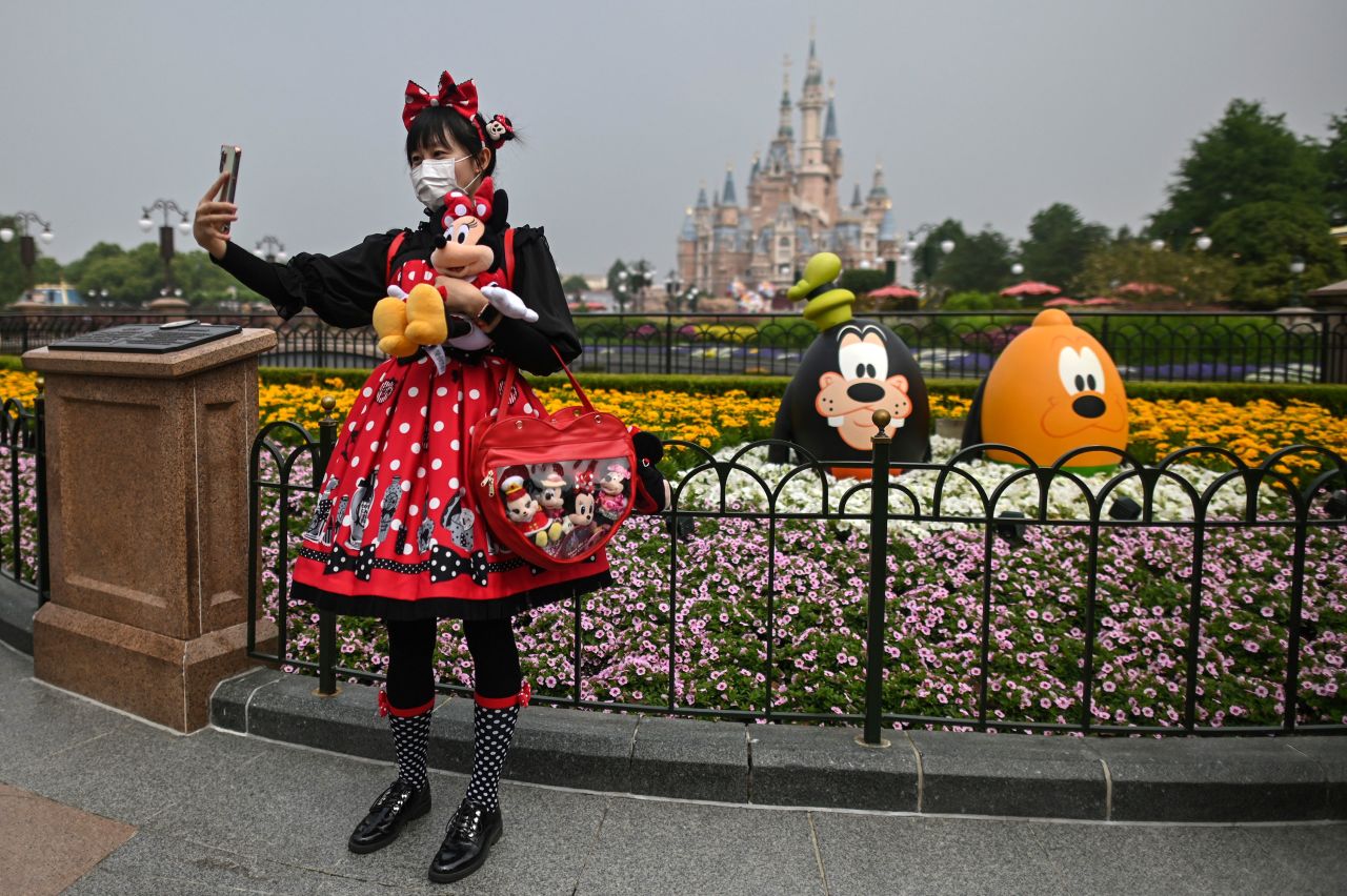A woman takes a photo at Disneyland Shanghai after the amusement park reopened in China on May 11. The park had been closed for three and a half months. Visitors are now required to wear masks, have their temperatures taken and practice social distancing.