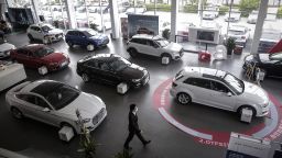 An employee wearing a protective mask walks past vehicles on display inside an Audi AG dealership in Wuhan, Hubei Province, China, on Monday, April 6, 2020.