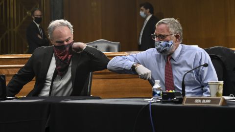 Sens. Tim Kaine, left, and Richard Burr greet each other with an elbow bump before the hearing.