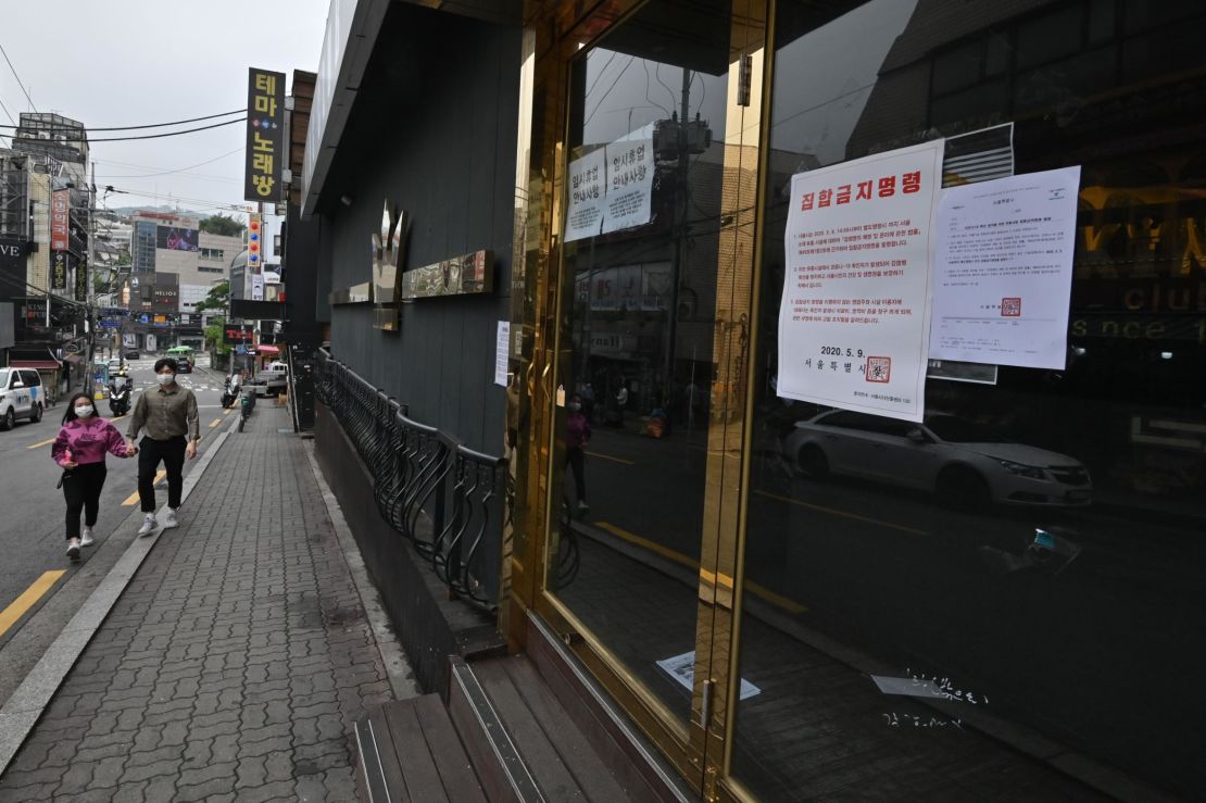 A couple wearing face masks walk past a night club, now closed following a visit by a confirmed Covid-19 coronavirus patient, in the popular nightlife district of Itaewon in Seoul on May 10, 2020.