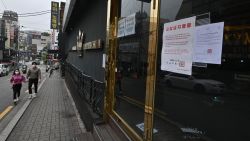 A couple wearing face masks walk past a night club, now closed following a visit by a confirmed COVID-19 coronavirus coronavirus patient, in the popular nightlife district of Itaewon in Seoul on May 10, 2020. - South Korea's capital has ordered the closure of all clubs and bars after a burst of new cases sparked fears of a second coronavirus wave as President Moon Jae-in urged the public to remain vigilant. (Photo by Jung Yeon-je / AFP) (Photo by JUNG YEON-JE/AFP via Getty Images)