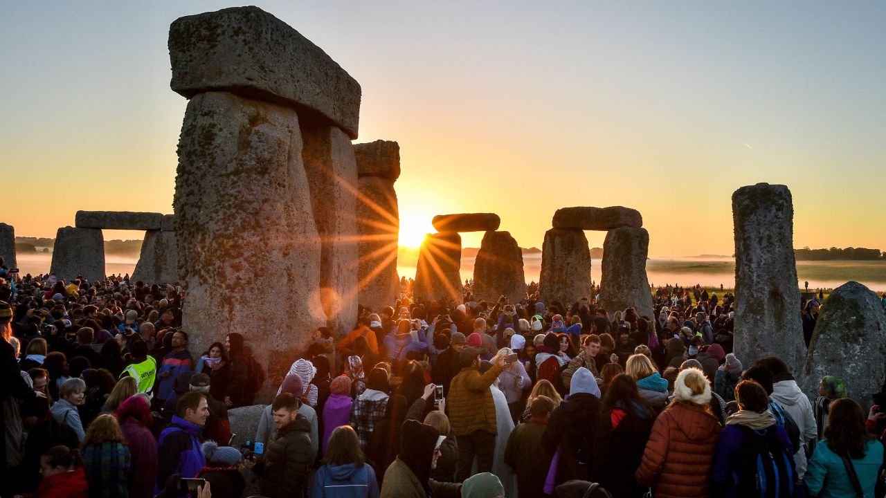 The sun rises between the stones and over crowds at Stonehenge where people gather to celebrate the dawn of the longest day in the UK. (Photo by Ben Birchall/PA Images via Getty Images)