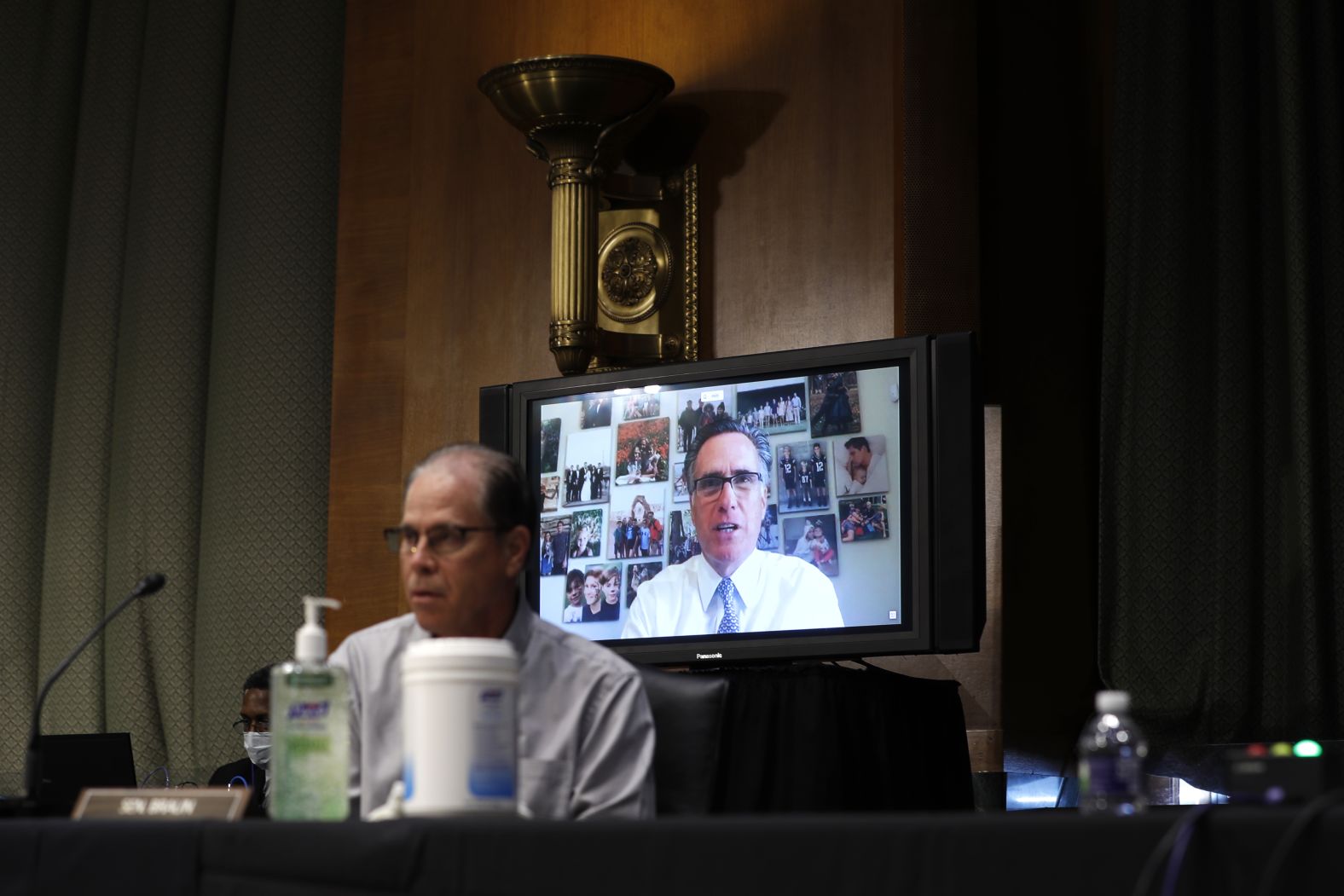Sen. Mitt Romney speaks via teleconference behind Sen. Mike Braun. "The President said the other day that President Obama is responsible for lack of vaccine. Dr. Fauci, is President Obama — or by extension President Trump — did they do something that made the likelihood of creating the vaccine less likely?" <a href="https://www.cnn.com/politics/live-news/fauci-testifies-coronavirus-05-12-2020/h_8b72e965e9227abdcef76327da4b499e" target="_blank">Romney asked.</a> Fauci said neither  Trump nor Obama are responsible for the lack of a coronavirus vaccine.