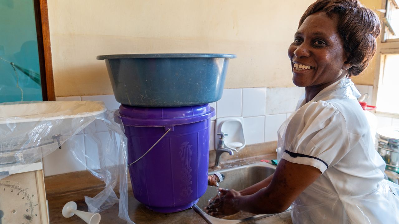 Patricia Mwenyeheri uses one of the two hand basins at the health center where she works. 