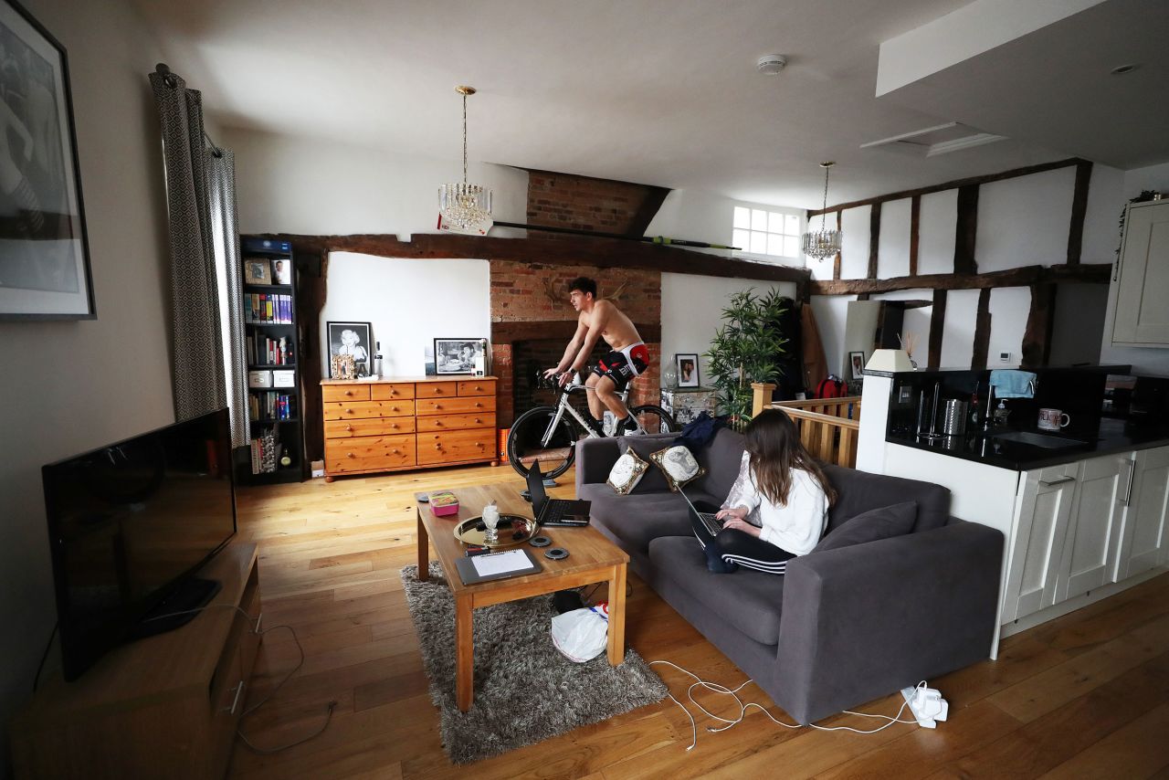 Paralympic rower James Fox rides a stationary bike while his girlfriend works from home in Henley-on-Thames, England, on April 1.