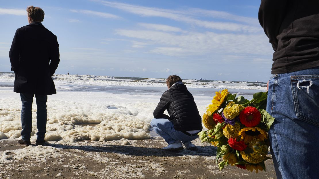 Relatives, friends and the surf community gather on The Hague Beach to mourn the loss of five surfers.