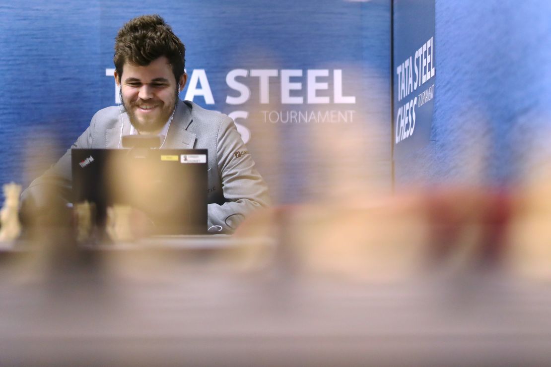 Carlsen speaks on his computer in a press room.