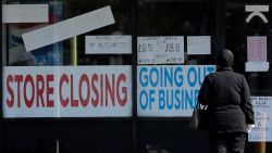 A woman looks at signs at a store closed due to COVID-19 in Niles, Ill., Wednesday, May 13, 2020. (AP Photo/Nam Y. Huh)