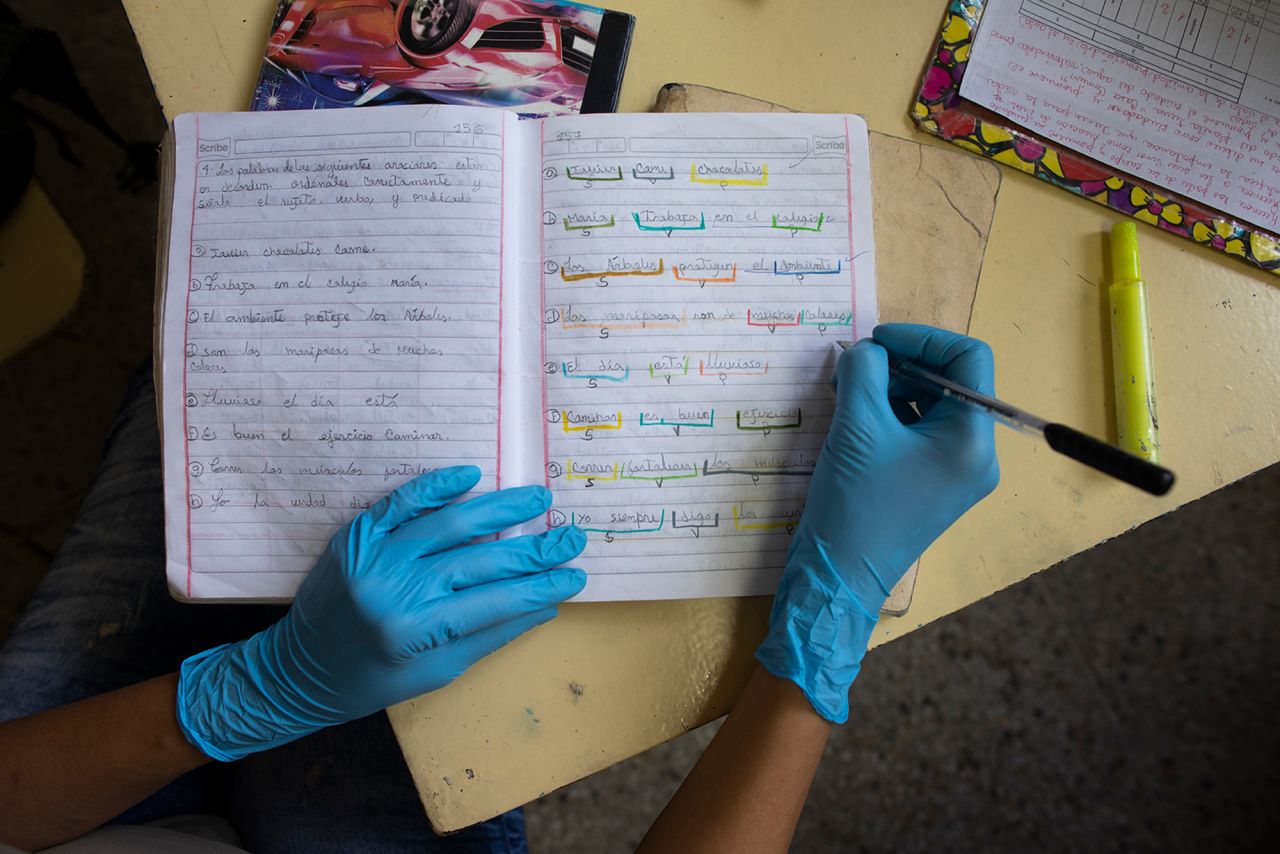 A teacher corrects a student's homework at the Fe y Alegria school, which was closed to in-class instruction in Caracas, Venezuela, on May 12. Parents without internet access bring their children's homework to the school.