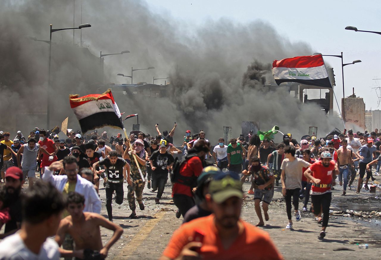 Anti-government protesters run for cover as they clash with security forces on the Al-Jumhuriyah bridge in Baghdad, Iraq, on Sunday, May 10.