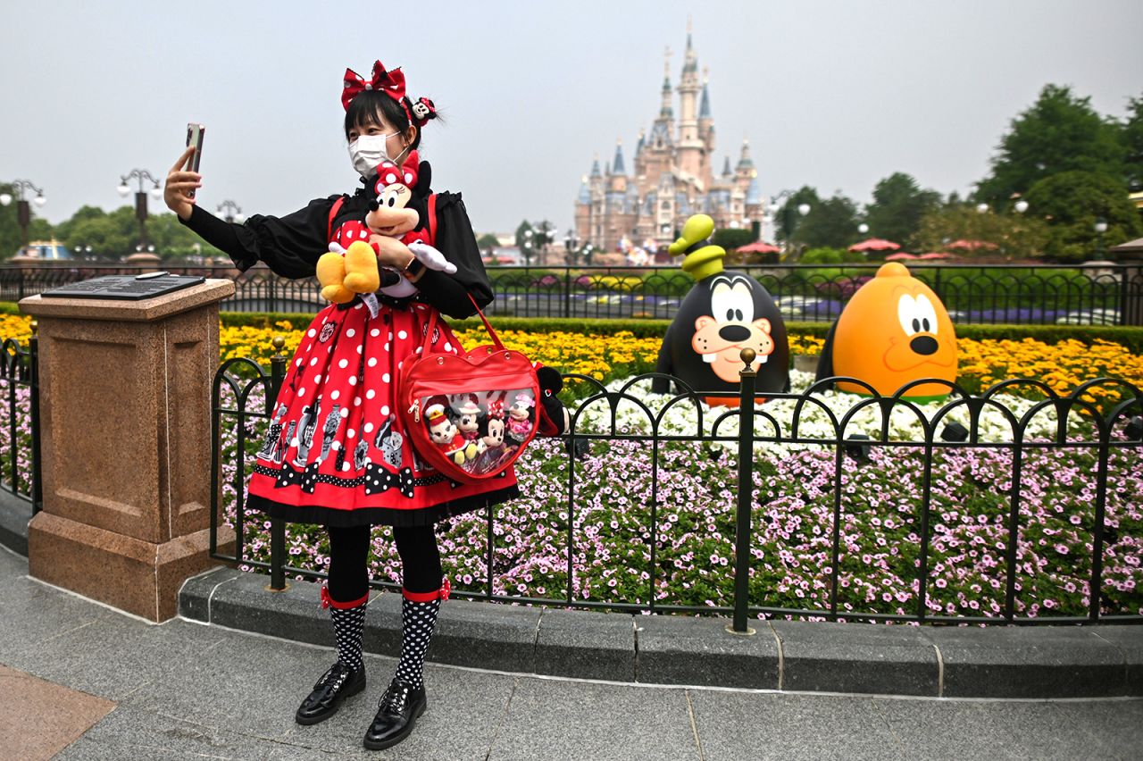 A woman takes a photo at Disneyland Shanghai after the amusement park reopened in China on Monday, May 11. The park had been closed for three and a half months. Visitors are now required to wear masks, have their temperatures taken and practice social distancing.