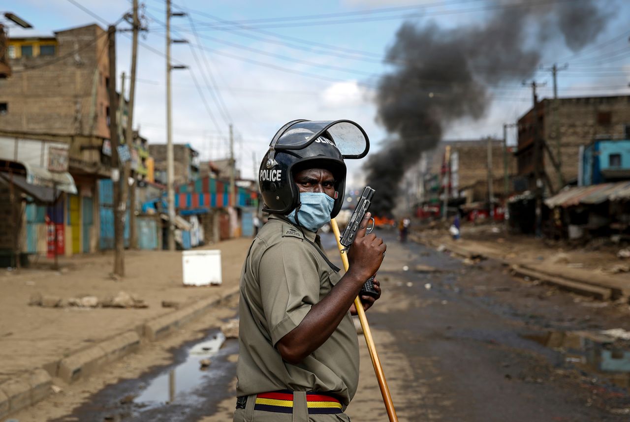 A police officer holds a pistol during clashes with protesters in Nairobi, Kenya, on Friday, May 8. Hundreds of protesters blocked one of the capital's major highways with burning tires to protest government demolitions of homes and the closure of a major food market.