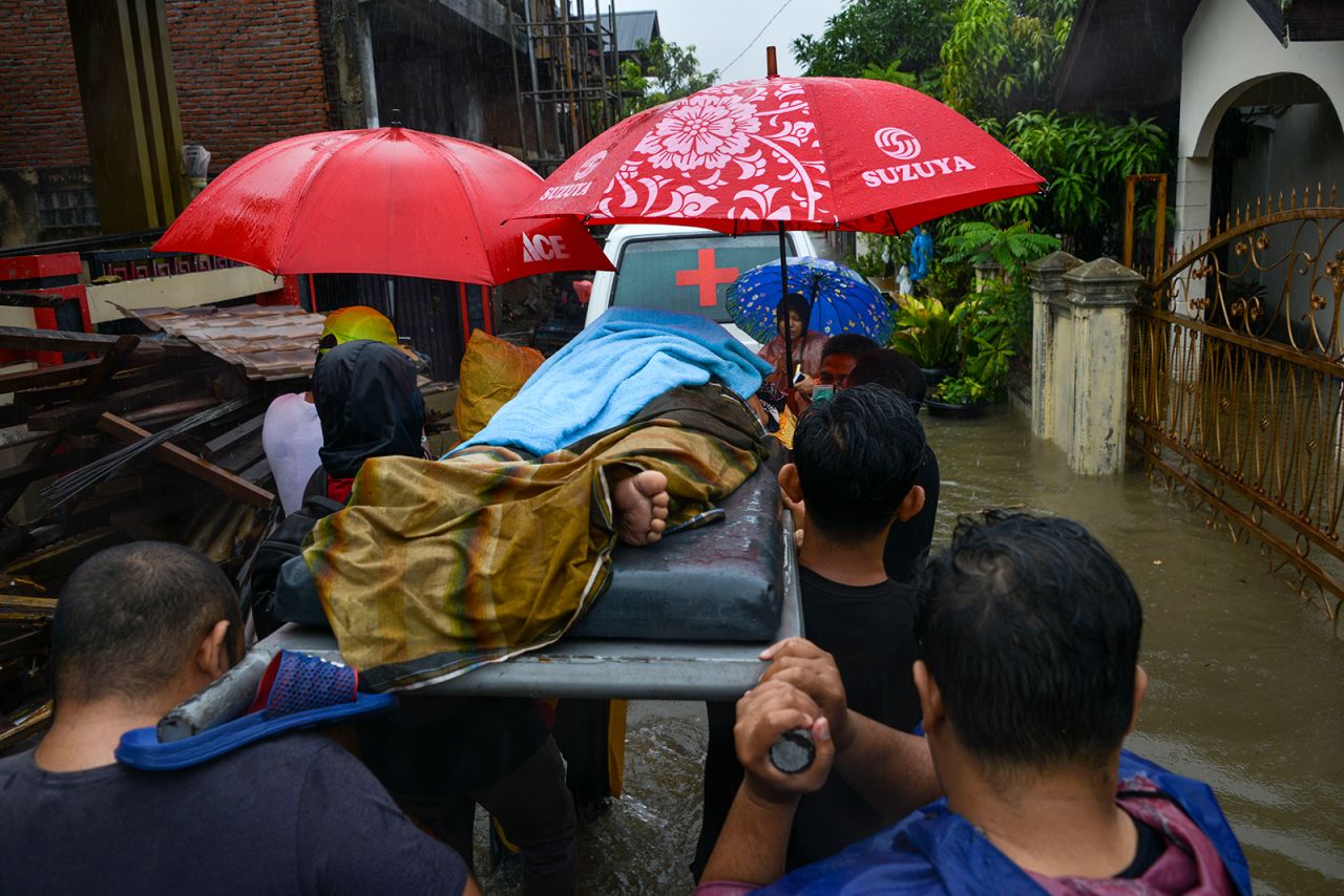 Medical workers help a woman evacuate a flooded residential area in Banda Aceh, Indonesia, on Friday, May 8.