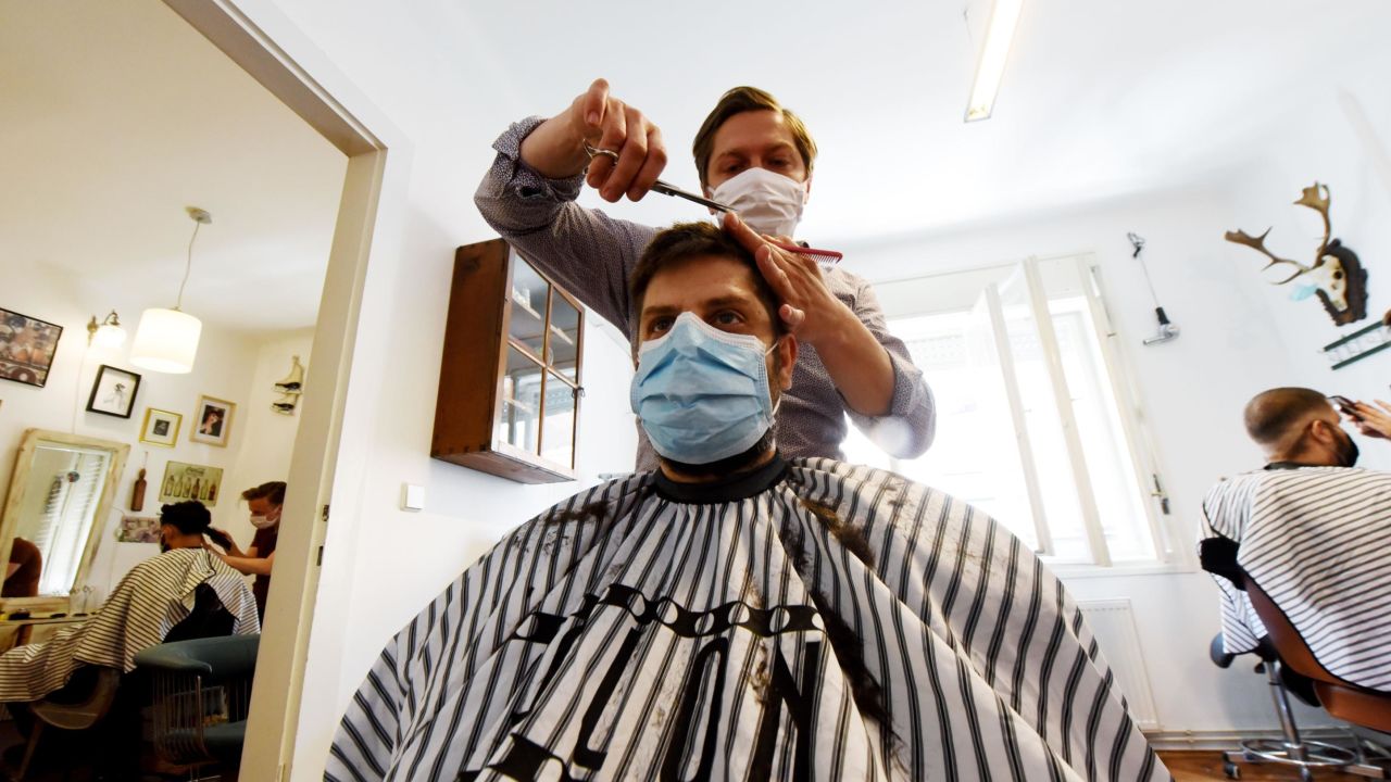 Hairdresser Marko Stanzl wears a face mask and cuts a client's hair in his salon in Zagreb, Croatia, on May 4, 2020, as the country started gradually loosening its pandemic lockdown.