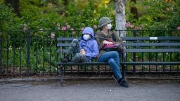 NEW YORK, NEW YORK - MAY 10: A mother and child wearing masks sit on a bench in Central Park amid the coronavirus pandemic on May 10, 2020 in New York City. COVID-19 has spread to most countries around the world, claiming over 283,000 lives with over 4.1 million cases. (Photo by Alexi Rosenfeld/Getty Images)