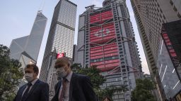 Pedestrians wearing protective masks walk as the HSBC Holdings Plc headquarters building, center, stands illuminated in the Central district of Hong Kong, China, on Monday, April 27, 2020. HSBC is scheduled to release first-quarter earnings results on April 28. Photographer: Roy Liu/Bloomberg via Getty Images