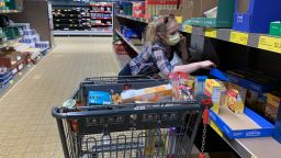 A woman gathers food after shoppers panic buy food at an Aldi grocery store in Bloomington. The woman on the right said, "I've got three kids, I've gotta do what I've gotta do." United States President Donald J. Trump declared a national emergency just hours earlier. (Photo by Jeremy Hogan/SOPA Images/Sipa USA/AP)