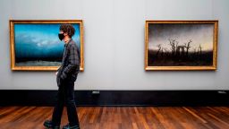 A visitor wearing a face mask walks past two paintings by Caspar David Friedrich at the Alte Nationalgalerie (Old National Gallery) museum in Berlin on May 12, 2020, after the museum re-opened its doors to the public following a relaxation of lockdown restrictions due to the new coronavirus COVID-19 pandemic. (Photo by John MACDOUGALL / AFP) / RESTRICTED TO EDITORIAL USE - MANDATORY MENTION OF THE ARTIST UPON PUBLICATION - TO ILLUSTRATE THE EVENT AS SPECIFIED IN THE CAPTION (Photo by JOHN MACDOUGALL/AFP via Getty Images)