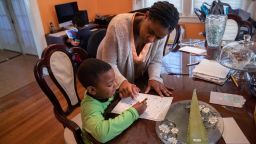 MOUNT VERNON, NY - MARCH 26: Geri Andre-Major helps her son Max, 5, with his school work on March 26, 2020 in Mount Vernon, New York. Andre-Major said she was furloughed as a pre-school teacher at Chelsea Piers Connecticut on March 13, four days after giving birth, and her maternity leave pay abruptly cut off as schools closed due to the coronavirus pandemic. Her husband was laid off as a chef consultant. The family left their apartment in New Rochelle, NY, hard hit by COVID-19, to live temporarily with Geri's parents. (Photo by John Moore/Getty Images)