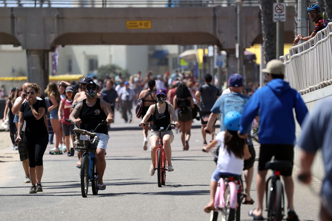 These people biking and walking along the beach in Huntington Beach, California, are mostly wearing masks since they're around strangers in public.