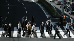 Pedestrians wearing protective masks cross a road in the Shinagawa district in Tokyo, Japan, on Thursday, May 14, 2020.