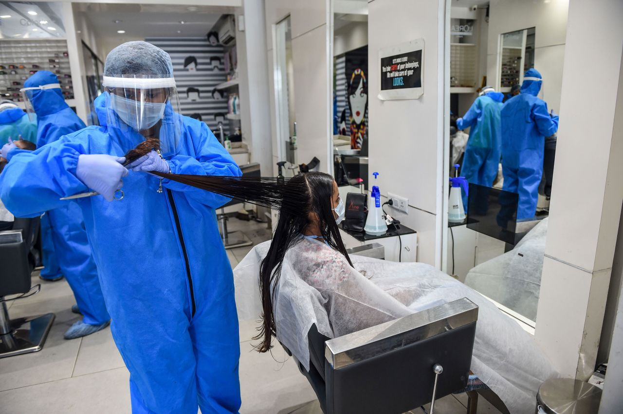 A worker wears protective gear while cutting a customer's hair at a salon in Nadiad, India, on May 17. India's lockdown was set to remain in place until May 31, but many salons and shops were able to reopen.