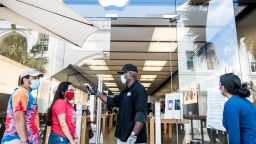 A security guard takes the temperature of a customer outside the Apple Store on May 13, 2020 in Charleston, South Carolina. Customers had their temperatures taken and were required to wear masks at the South Carolina store, as locations in Idaho, Alabama, and Alaska reopened as well following forced closures due to the coronavirus. (Photo by Sean Rayford/Getty Images)