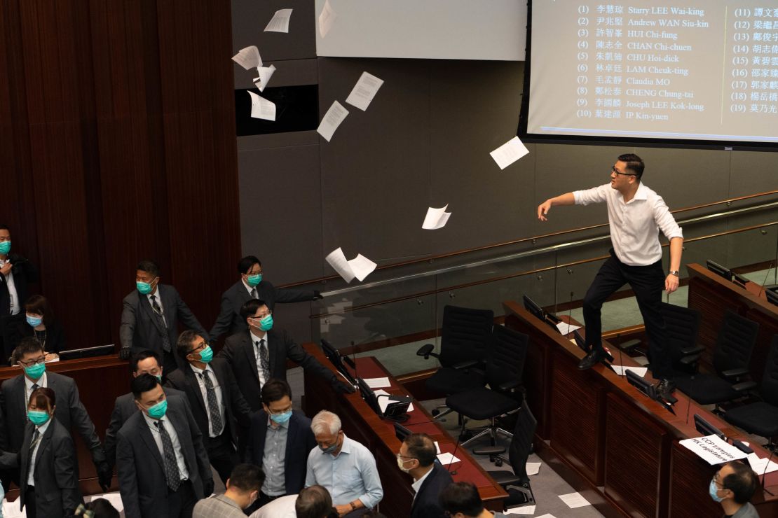 Lam Cheuk-ting, a pro-democracy lawmaker, right, tosses papers into the air in protest as security officers look on.