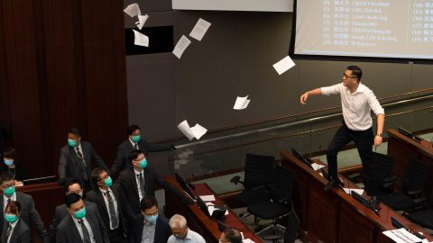 Lam Cheuk-ting, a pro-democracy lawmaker, right, tosses papers into the air in protest as security officers look on.