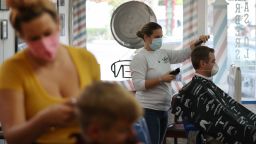 FORT LAUDERDALE, FLORIDA - MAY 18: Angie O'Neill works on the hair of Phil Quinn as the Las Olas Barber shop opens on May 18, 2020 in Fort Lauderdale, Florida. The barbershop re-opened, approximately two months after shutting it's doors due to the coronavirus pandemic, as Broward County starts the first phase of the states coronavirus pandemic re-opening plan, which includes openings with certain restrictions of businesses like barbershops, restaurants and retail stores. (Photo by Joe Raedle/Getty Images)