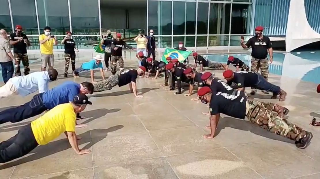 Bolsonaro (left, blue shirt) does push-ups at an event in Brasilia on Sunday.