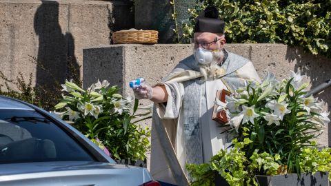 Father Tim Pelc douses a vehicle during the Easter blessing of baskets.