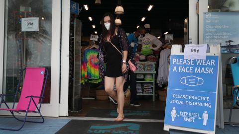 A customer in a face mask exits the Surf Style store, which reopened Monday, in Fort Lauderdale.
