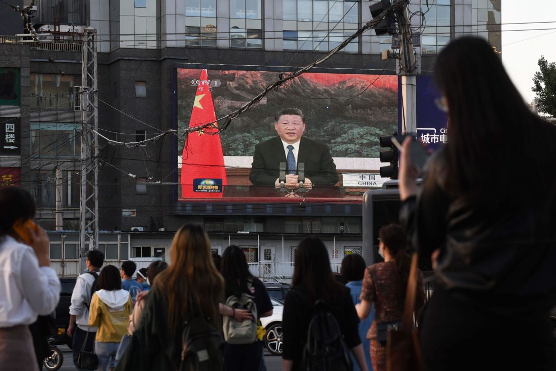 A news program shows Chinese President Xi Jinping speaking via video link to the World Health Assembly on a giant screen beside a street in Beijing on May 18.