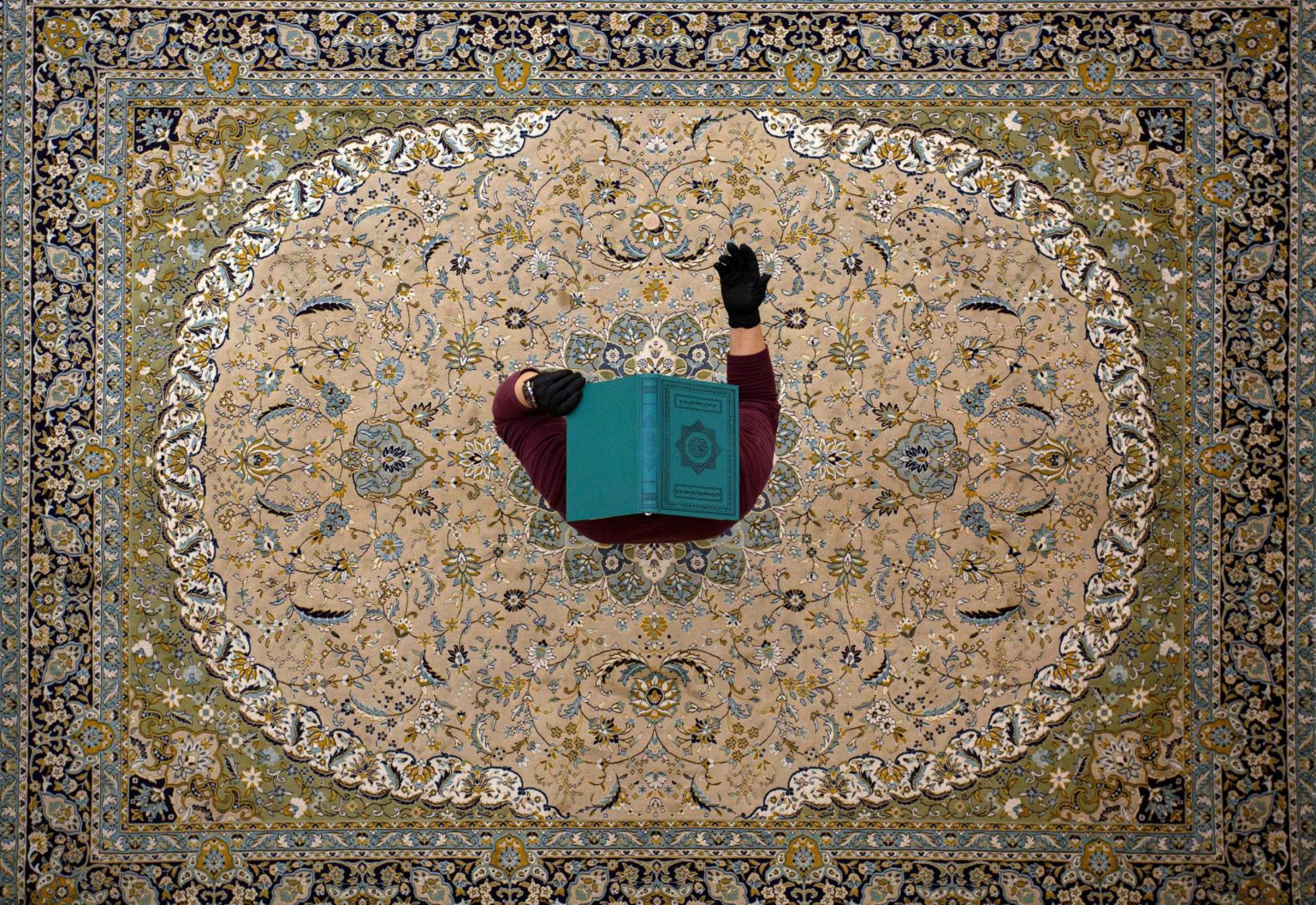 A young man covers his head with the Quran at a mosque in Basra, Iraq, on Sunday, May 17. He was showing respect on Laylat al-Qadr, believed to be Islam's holiest night of the year.