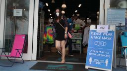 A customers walks past a sign reading, ' please wear  face mask,' after the Surf Style store opened on May 18, 2020 in Fort Lauderdale, Florida. The store opened, approximately two months after shutting it's doors due to the coronavirus pandemic, as Broward County starts the first phase of the states coronavirus pandemic re-opening plan, which includes openings with certain restrictions of businesses like barbershops, restaurants and retail stores. 