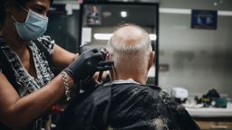 A stylist wearing a protective mask and gloves cuts a customer's hair at a barber shop in Coral Gables, Florida, U.S., on Monday, May 18, 2020. Florida Governor Ron DeSantis announced a partial re-opening order in Miami-Dade county, the two counties hardest hit by the coronavirus outbreak. 