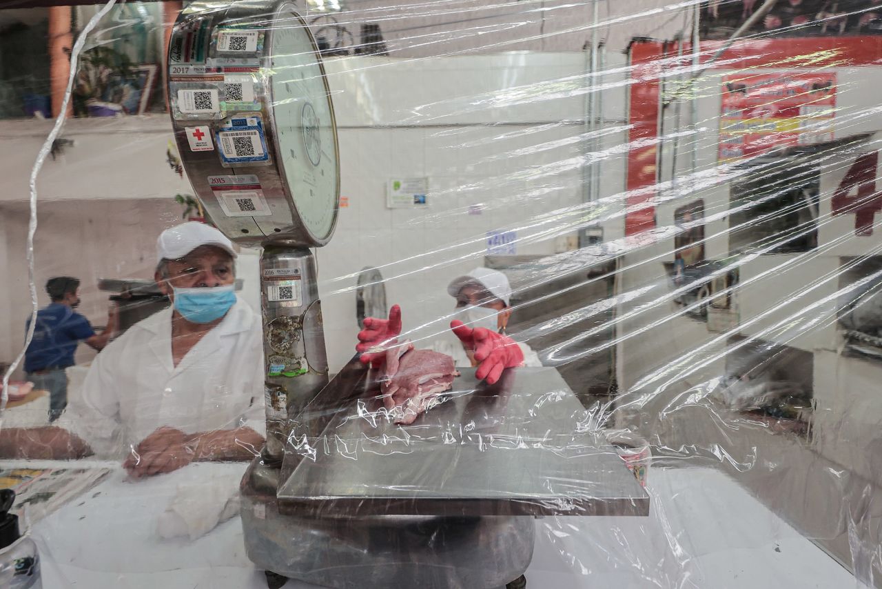Butchers in Mexico City weigh meat behind a plastic curtain on May 18.