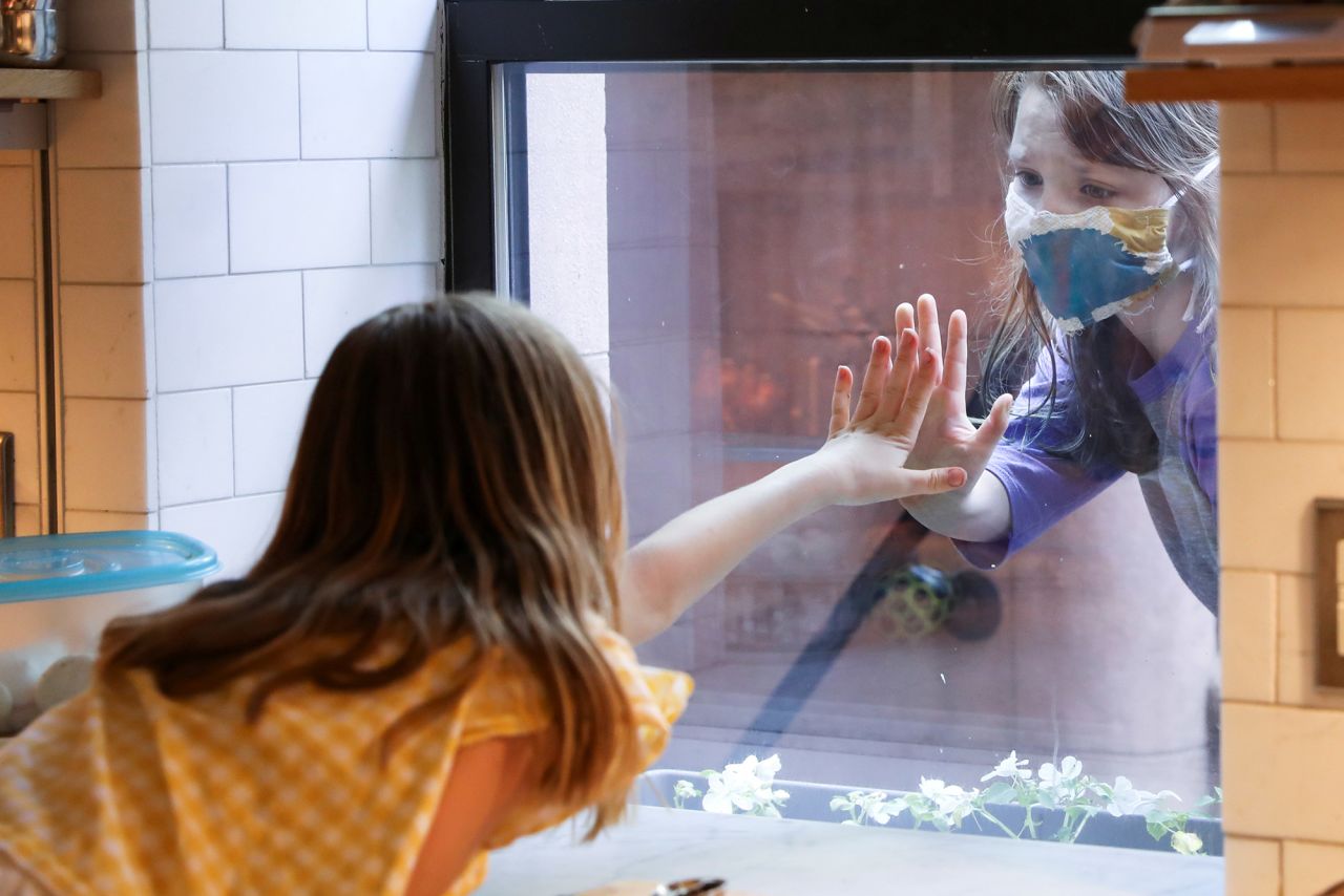 Lydia Hassebroek greets her friend Rose through her kitchen window in New York on May 17.
