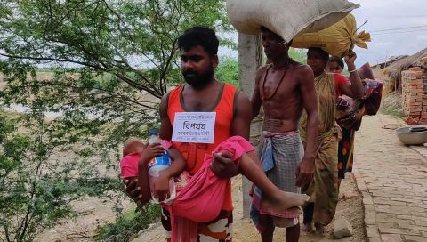 A disaster management volunteer carries a child as villagers evacuate Bakkhali, India, on the Bay of Bengal coast.
