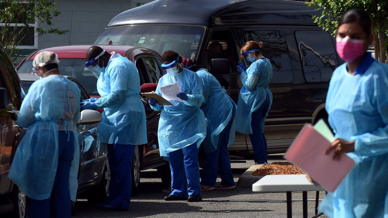 People arrive in cars at a mobile COVID-19 testing site at the Westside Community Center in the Goldsboro neighborhood of Sanford, Florida on April 23, 2020. Local health officials are offering the free tests at six historic black communities in Seminole County to help residents who are not only especially vulnerable to coronavirus, but who cannot drive to a health clinic or may be unable to afford health insurance.