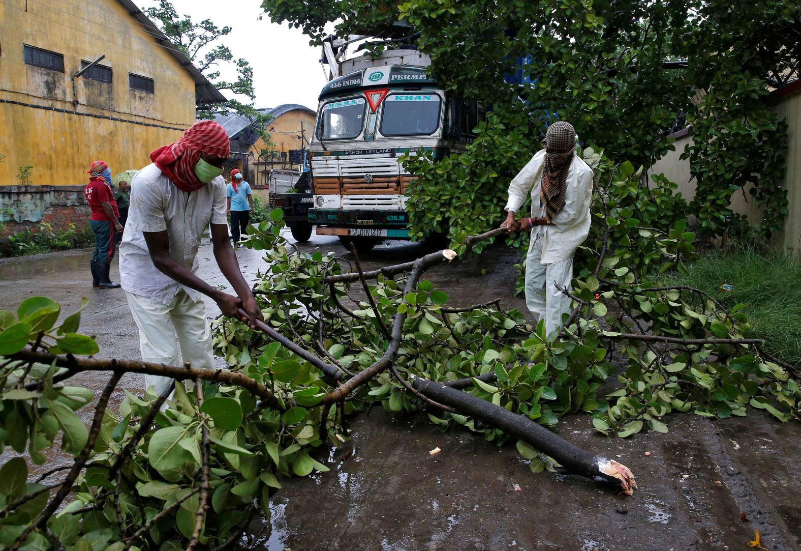 Rescue workers in Kolkata cut tree branches that fell on a truck due to heavy winds.