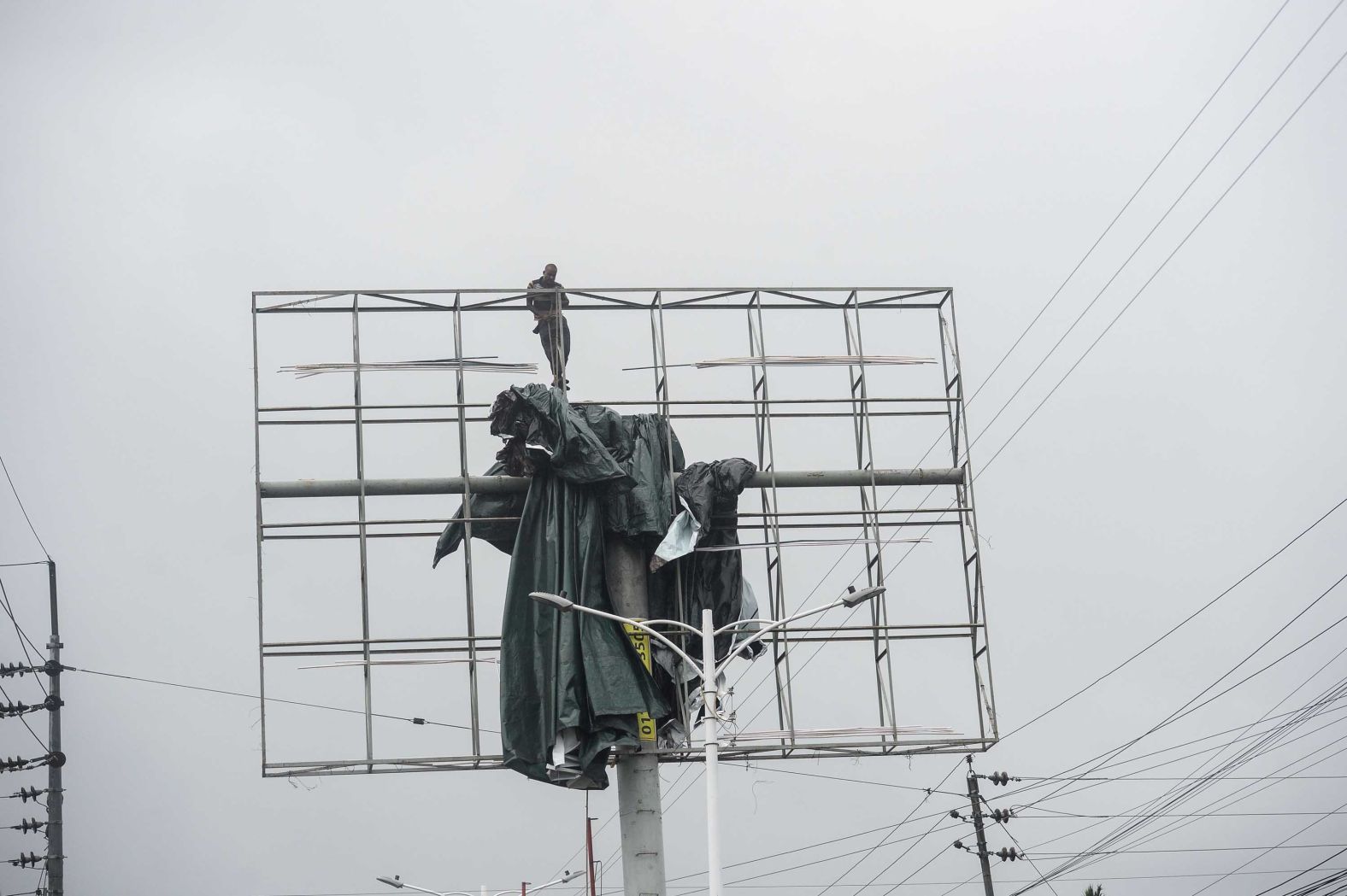 A worker removes a tarp from an advertising structure in Khulna, Bangladesh.