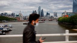 A pedestrian walks on Waterloo Bridge to cross the River Thames, backdropped by the skyscrapers and office buildings of the City of London, on May 13, 2020, as people start to return to work after COVID-19 lockdown restrictions were eased. - Britain's economy shrank two percent in the first three months of the year, rocked by the fallout from the coronavirus pandemic, official data showed Wednesday, with analysts predicting even worse to come. (Photo by Tolga Akmen/AFP/Getty Images)