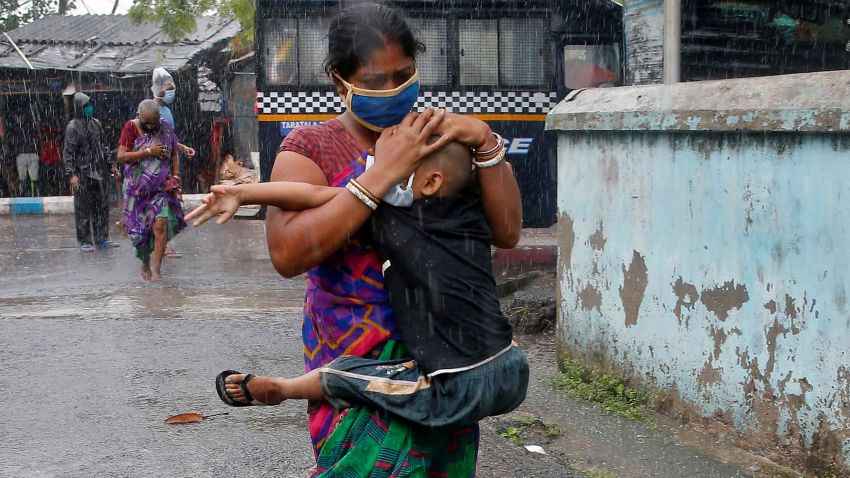A woman carries her son as she tries to protect him from heavy rain while they rush to a safer place, following their evacuation from a slum area before Cyclone Amphan makes its landfall, in Kolkata, India, May 20, 2020. REUTERS/Rupak De Chowdhuri