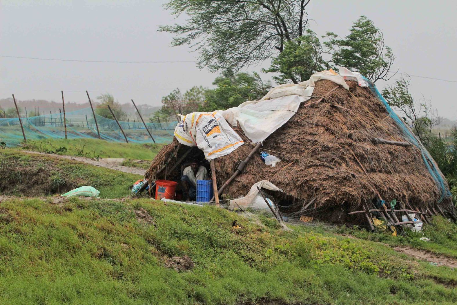 A man takes shelter inside a hut in India's Bhadrak district.