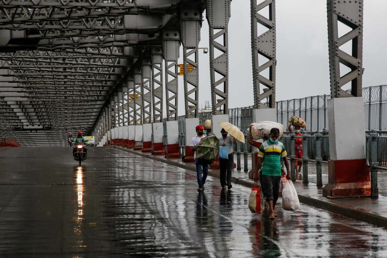 Commuters make their way along the Howrah Bridge in Kolkata as it rains on May 20.