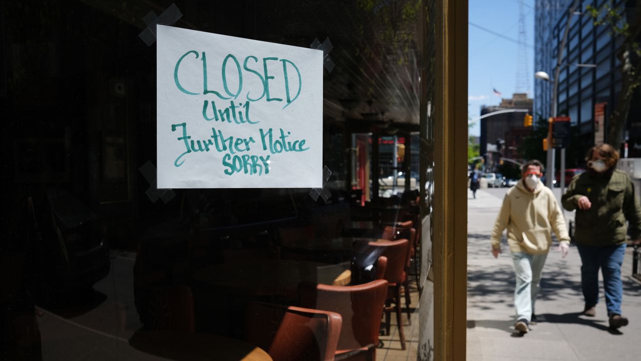 NEW YORK CITY- MAY 12:  People walk through a shuttered business district in Brooklyn on May 12, 2020 in New York City. Across America, people are reeling from the loss of jobs and incomes as unemployment soars to historical levels following the COVID-19 outbreak. While some states are beginning to re-open slowly, many business are struggling to find a profit with the news restrictions and a population that is fearful of the contagious virus.  (Photo by Spencer Platt/Getty Images)