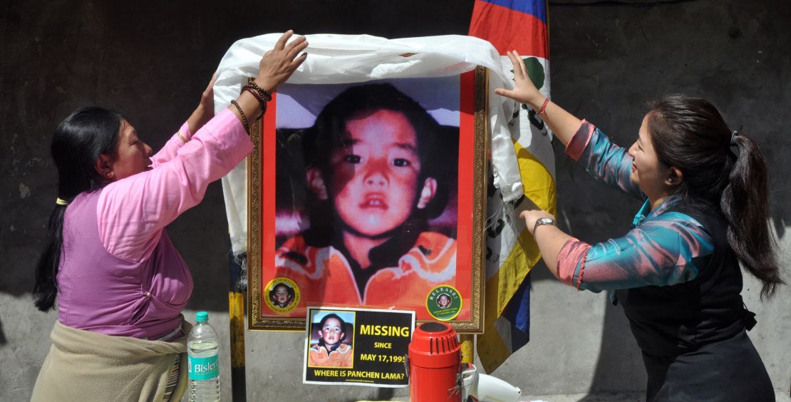 Two women place a ceremonial scarf above a portrait showing the last know image of Gedhun Choekyi Nyima, in Mcleodganj near Dharamsala, India, on April 25, 2017.