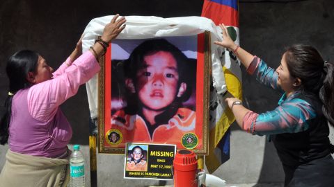 Two women place a ceremonial scarf above a portrait showing the last know image of Gedhun Choekyi Nyima, in Mcleodganj near Dharamsala, India, on April 25, 2017.